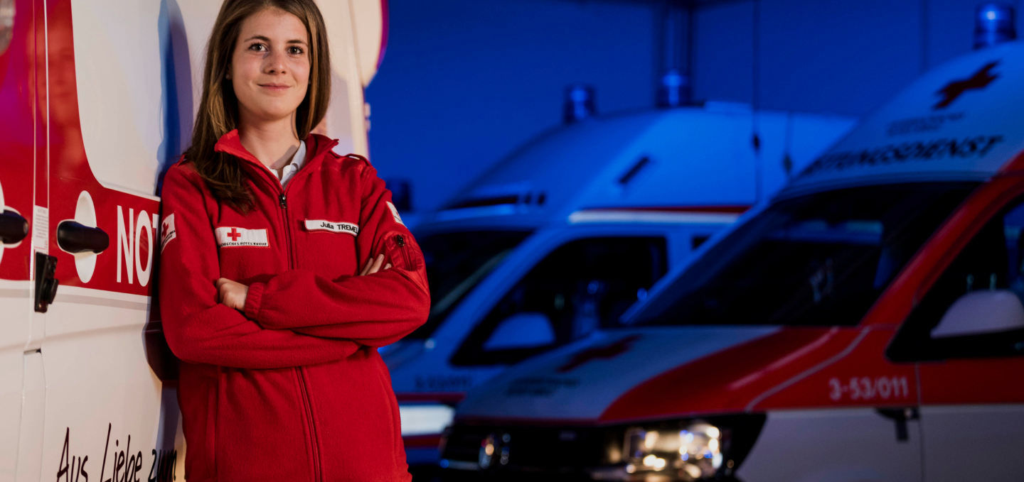Junge Frau mit einer Rotes-Kreuz-Jacke lächelt in die Kamera